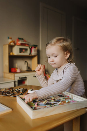 Portrait of toddler girl playing with toys in playroom. Adorable two years old girl at home, enjoying creative playtime in a bright, cozy environment. Generation alpha concept. Part of a series.の写真素材