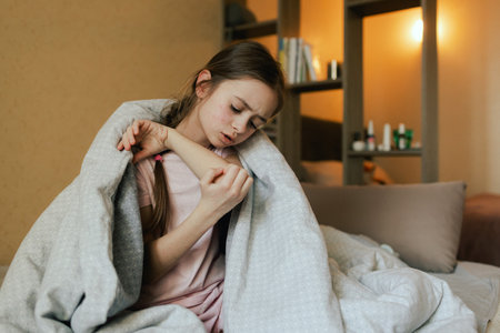 Close up of sick child with skin rashes is scratching from an itch in bed. Allergic reaction, Drug allergy, Scarlet fever, Atopic dermatitis, Diaper rash, Urticaria, Scabies, Heat rash. Part of a series.の写真素材