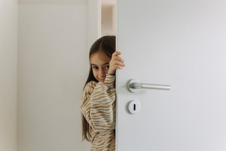 Photo of Expression of female teenager at home. A teenage girl is hiding behind the door.の写真素材