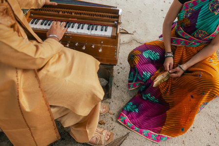 Close-up of Indian musician in traditional clothes playing sitar for young woman in traditional...