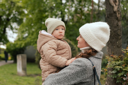 Mother with her daughter outdoors, close-up. A woman and a child are walking in the park in the cold...