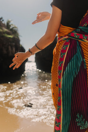 Indian woman in traditional saree clothes on the nature with the ocean on background. Indian festival costume. Concept of solo tourism and travel to India. Part of a seriesの写真素材
