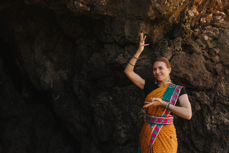 Indian woman in traditional saree clothes dances traditional dances on the nature with the ocean on...