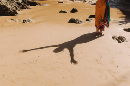 Indian woman in traditional saree clothes is happy with life and raises her hands up on the ocean background. Indian festival costume. Concept of solo tourism and travel to India. Part of a seriesの写真素材