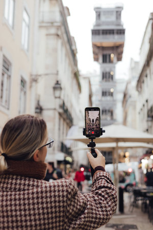 Vlogger traveler woman recording video on phone share via app travel vacation. Middle age woman influencer shooting social media stories on elevator to the observation deck in center of Lisbon. UGCの写真素材
