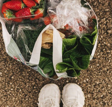 Reusable bag filled with various fruits and vegetables standing on the floor. Close-up, top view....