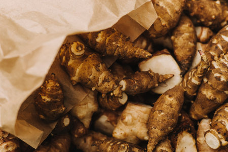 Group of fresh jerusalem artichokes in a paper bag. Jerusalem artichokes or sunroot or sunchoke. Vegetarian food. Close-up, top viewの写真素材