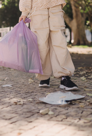 Close-up of a teenager's feet with a garbage bag on the public park. Volunteers help to keep nature clean up and pick up garbage. Environmental cleanup concept.の写真素材
