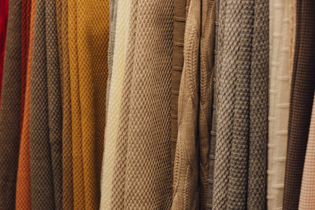 Choice of blanket of different colors on wooden hangers in a retail shop. Home comfort concept.