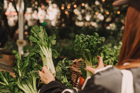 Close up of woman buying greens on the local Farmers market. Mature Female Customer Shopping At Farmers Market Stall. Close up. Part of the series.の写真素材