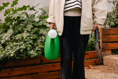Close-up of woman with garden tools as florist taking care of flowers and plants in garden eco-farm. Concept green tourism, slow life, gardening, eco friendly. Part of the seriesの写真素材