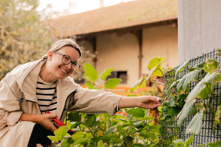 Close-up of woman with garden tools as florist taking care of flowers and plants in garden eco-farm. Concept green tourism, slow life, gardening, eco friendly. Part of the seriesの写真素材
