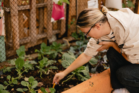 Portrait of a middle-aged woman as florist taking care of flowers and plants in garden with greenhouse eco-farm. Concept green tourism, slow life, gardening, eco friendly. Part of the seriesの写真素材