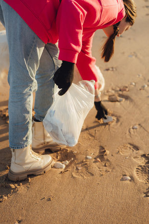 Close-up of ecologist volunteer's hands cleans the beach on the seashore from plastic and other waste. Garbage recycle and environmental care concept. Part of a seriesの写真素材