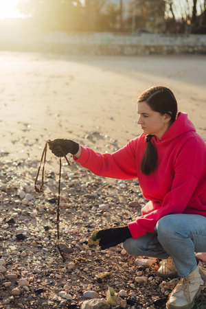 A female ecologist volunteer cleans the beach on the seashore from plastic and other waste. Garbage recycle and environmental care concept. Part of a seriesの写真素材
