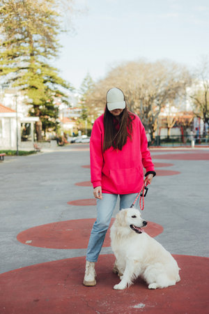 Young woman trains golden retriever puppy in the park in sunny weather. Happy dogs concept. Part of a seriesの写真素材