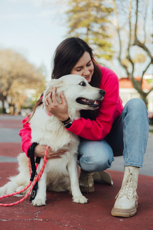 Young woman trains golden retriever puppy in the park in sunny weather. Happy dogs concept. Part of...