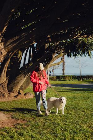 Young woman trains golden retriever puppy in the park in sunny weather. Happy dogs concept. Part of...