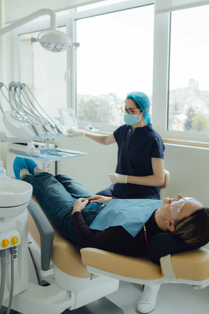 Smiling mature woman at dental check-up with young female dentist. Appointment at clinic. Tooth...