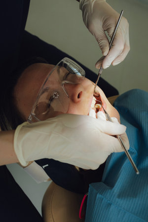 Smiling mature woman at dental check-up with young female dentist. Appointment at clinic. Tooth whitening, cleaning or oral, mouth and gum care at hospital. Soft focus. Part of a series. Close-up.の写真素材