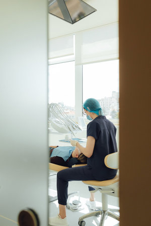 Smiling mature woman at dental check-up with young female dentist. Appointment at clinic. Tooth whitening, cleaning or oral, mouth and gum care at hospital. Soft focus. Part of a series. Close-up.の写真素材