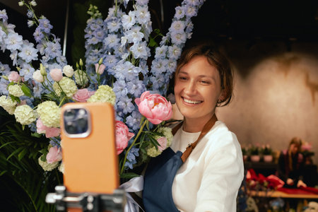 Small flower shop. A woman writes a video blog or online course. Flower school concept. Florist...