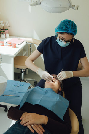 Smiling mature woman at dental check-up with young female dentist. Appointment at clinic. Tooth...