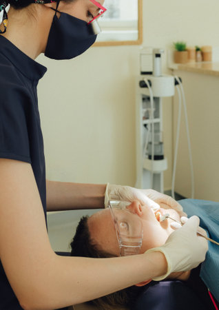 Smiling mature woman at dental check-up with young female dentist. Appointment at clinic. Tooth whitening, cleaning or oral, mouth and gum care at hospital. Soft focus. Part of a series. Close-up.の写真素材