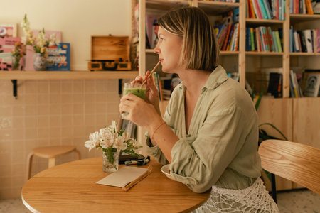 Middle-aged woman scrolls her social media feed on mobile phone in a cozy cafe. Small business. Using phone for business, online shopping, transfer money, financial, internet banking. Part of a seriesの写真素材