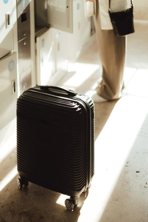 Traveler woman with suitcase in the luggage storage room at train station. Business travel and solo...