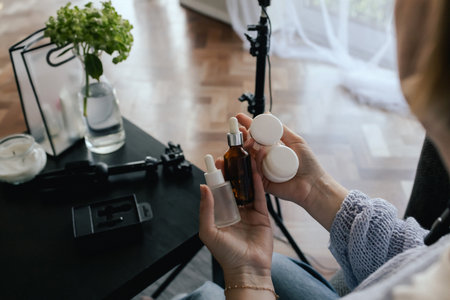 Middle-aged woman beauty blogger filming skincare product unboxing at home with ring light. User-generated content UGC for online store promotion. Vlogger live streaming. Part of a seriesの写真素材