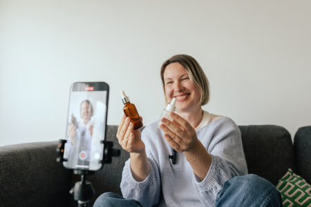 Middle-aged woman beauty blogger filming skincare product unboxing at home with ring light. User-generated content UGC for online store promotion. Vlogger live streaming. Part of a seriesの写真素材
