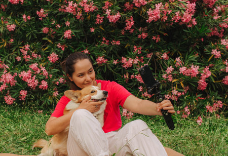 Young girl with Corgi recording video on phone share via app her travel vacation. Gen Z influencer shooting social media stories. Concept of friendship between a dog and human. Part of a series. UGCの写真素材