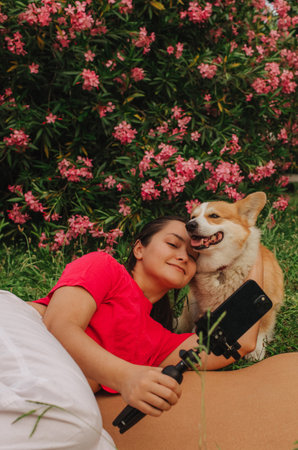 Young girl with Corgi recording video on phone share via app her travel vacation. Gen Z influencer shooting social media stories. Concept of friendship between a dog and human. Part of a series. UGCの写真素材
