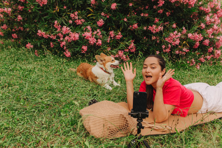 Young girl with Corgi recording video on phone share via app her travel vacation. Gen Z influencer shooting social media stories. Concept of friendship between a dog and human. Part of a series. UGCの写真素材
