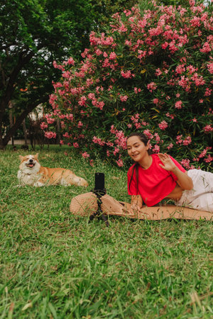 Young girl with Corgi recording video on phone share via app her travel vacation. Gen Z influencer shooting social media stories. Concept of friendship between a dog and human. Part of a series. UGCの写真素材