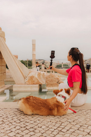 Young girl with Corgi recording video on phone share via app her travel vacation. Gen Z influencer shooting social media stories. Concept of friendship between a dog and human. Part of a series. UGCの写真素材