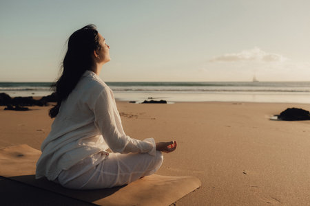 Asian woman in white clothes practice yoga for meditation and relaxation for healthy near seaside. Healthcare exercise and yoga concept. Solo tourism. Part of a series.の写真素材
