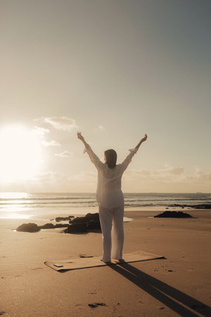 A cheerful free woman on the beach, ocean, unity with nature, healthy lifestyle. Healthcare exercise and yoga concept. Solo tourism. Part of a series.の写真素材