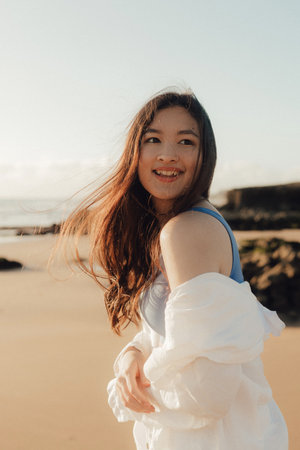 A cheerful free woman on the beach, ocean, unity with nature, healthy lifestyle. Healthcare exercise and yoga concept. Solo tourism. Part of a series.の写真素材