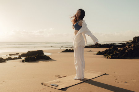 A cheerful free woman on the beach, ocean, unity with nature, healthy lifestyle. Healthcare exercise and yoga concept. Solo tourism. Part of a series.の写真素材