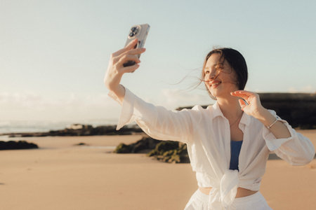 Young girl recording video on phone share via app her travel vacation near seaside. Gen Z influencer shooting social media stories. Part of a series. UGCの写真素材