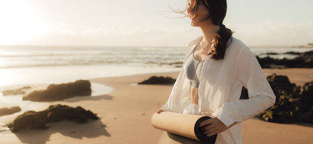 Asian happy woman in white clothes with yoga mat on the ocean shore. Concept of health exercises and yoga. Tourism alone. Part of series.の写真素材
