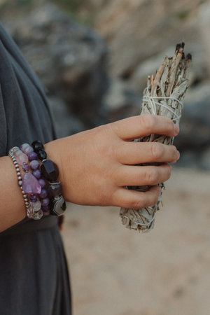 Close-up of female hands holding natural incense. Tools for ritual, energetic cleansing, and inner peace through aroma, intention, and mindful presence. Vintage tone. Soft focus, blurredの写真素材