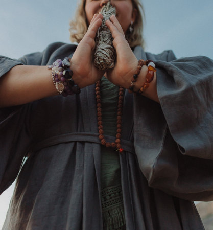 Close-up of female hands holding natural incense. Tools for ritual, energetic cleansing, and inner peace through aroma, intention, and mindful presence. Vintage tone. Soft focus, blurredの写真素材