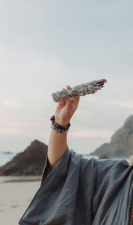 Close-up of female hands holding natural incense. Tools for ritual, energetic cleansing, and inner peace through aroma, intention, and mindful presence. Vintage tone. Soft focus, blurredの写真素材