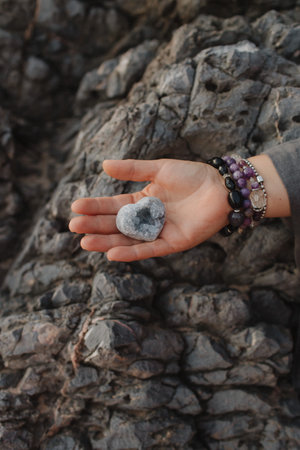 Close-up of female hands holding natural healing stones. Tools for energy balance, emotional support, self-discovery through intention, intuition, gentle presence. Vintage tone. Soft focus, blurred.の写真素材
