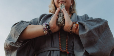 Close-up of female hands holding natural incense. Tools for ritual, energetic cleansing, and inner peace through aroma, intention, and mindful presence. Vintage tone. Soft focus, blurredの写真素材