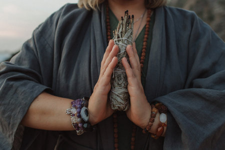 Close-up of female hands holding natural incense. Tools for ritual, energetic cleansing, and inner peace through aroma, intention, and mindful presence. Vintage tone. Soft focus, blurredの写真素材