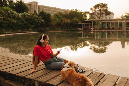 Close-up of a woman with Welsh Corgi in a park on a hot sunny day. The dog looks tired from the heat. Concept of summer walk, pet care, and companionship. Soft focus. Part of a series.の写真素材